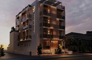 Ein mehrstöckiges Hotel mit modernem Design, mit Balkonen, einem markanten Eingang und einer gut beleuchteten Fassade.