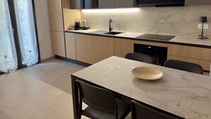 Una cuina moderna amb taulell de marbre, forn de mur i rentaplats.