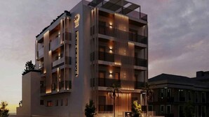 Um hotel com vários andares e design moderno, com varandas, entrada destacada e fachada bem iluminada.