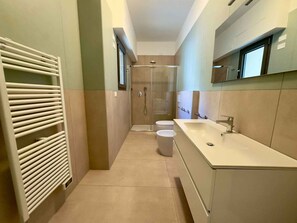 Ein modernes Badezimmer mit begehbarer Dusche, Toilette und großem Waschbecken.