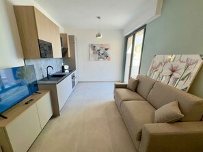 Eine moderne Küche mit Flachbildfernseher, Essbereich und einer Couch.