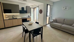 Une cuisine moderne avec une table et des chaises, un canapé et une grande fenêtre.