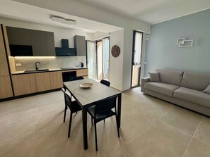 Eine moderne Küche mit Esstisch und Stühlen, einer Couch und einem großen Fenster.