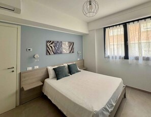 A bedroom with a bed, a wall-mounted artwork, a window with curtains, and a ceiling light fixture. - Holiday apartment with air conditioning, internet and balcony with sea view (Pesaro)
