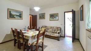 Un área de comedor con una mesa preparada para cuatro, un sofá floral y tres cuadros en las paredes.