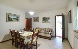 A dining area with a table set for four, a floral sofa, and three framed artworks on the walls. - 2 bedroom stunning home in Camaiore (Camaiore)