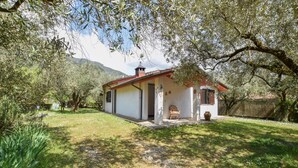 Una casita con techo rojo, un porche y un jardín.