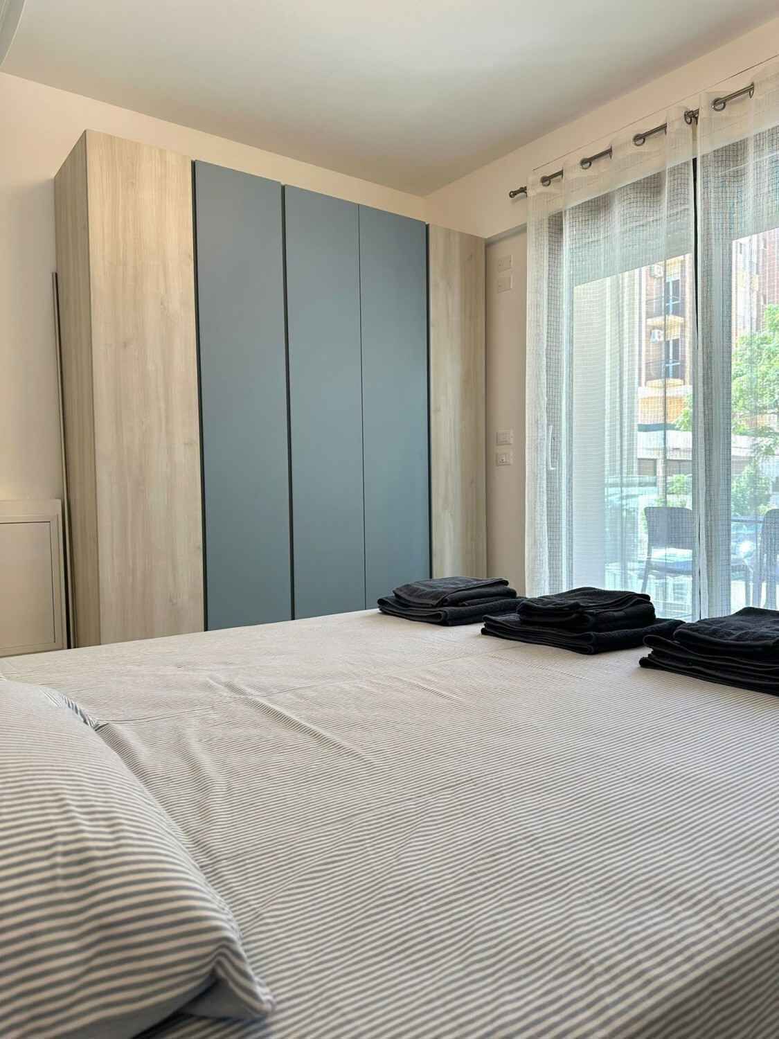 Habitació d'hotel amb un llit, un armari i una finestra amb cortines.