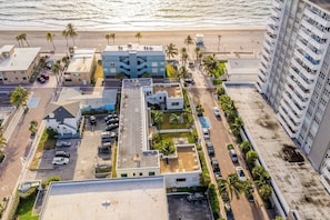Eine Vogelperspektive eines Küstenhotels mit mehreren Gebäuden, Parkplätzen und einem Strand im Hintergrund.