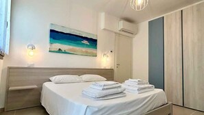 Une chambre moderne avec un lit, un tableau, un appareil de climatisation et un luminaire.