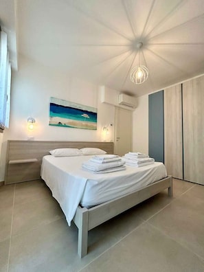 Ein modernes Schlafzimmer mit einem Bett, einem Gemälde, einer Klimaanlage und einer Leuchte.