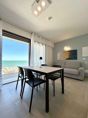 Ein modernes Wohnzimmer mit Essbereich, einer Couch und Blick auf den Strand.