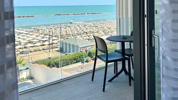 Un balcon avec vue sur la plage, une table et des chaises.