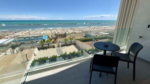 Un balcon avec vue sur une plage, une piscine et le paysage urbain.