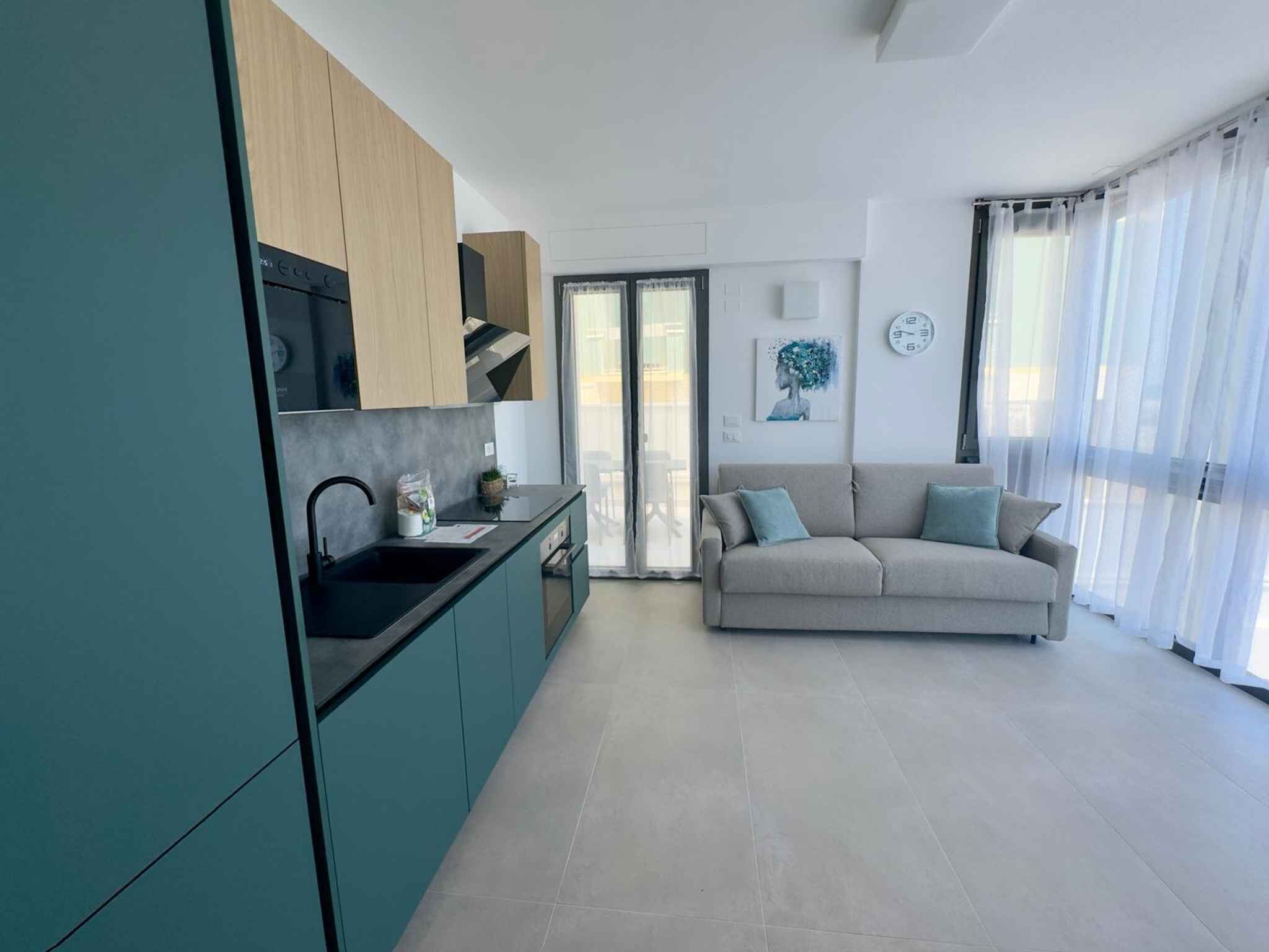 A modern kitchen with a sink, cabinets, and a dining area with a sofa.