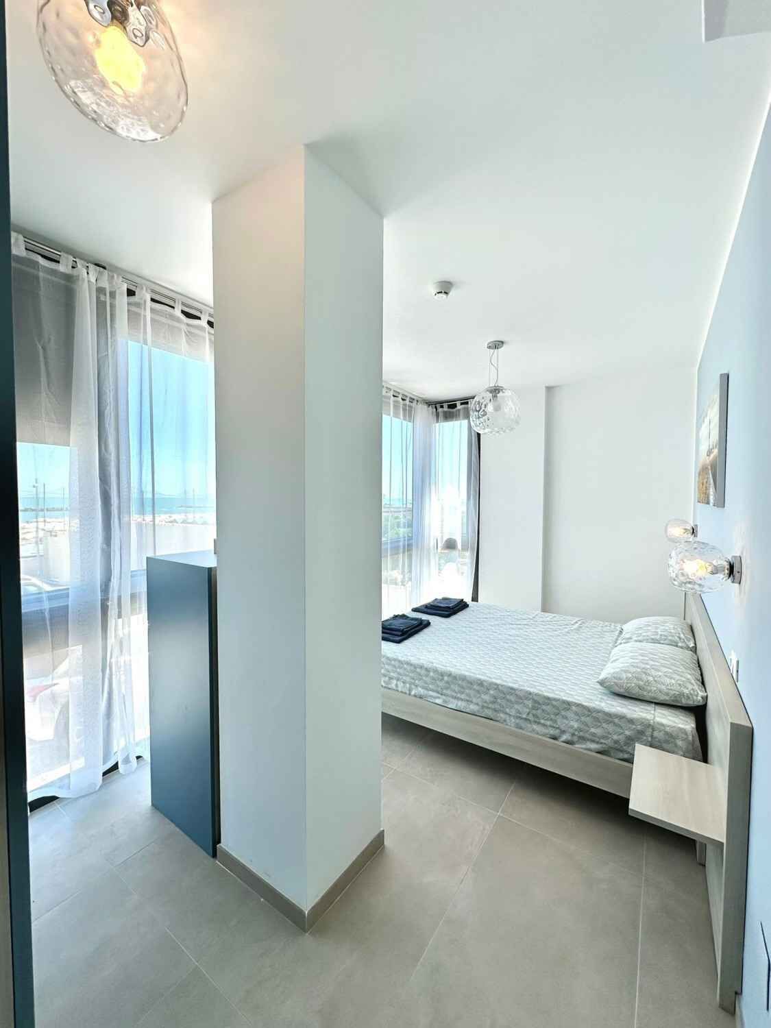 Een moderne slaapkamer met een bed, een hanglamp en uitzicht door een raam.