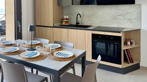Una cocina moderna con armarios de madera, un microondas negro, un fregadero y una zona de comedor con una mesa preparada para cuatro.