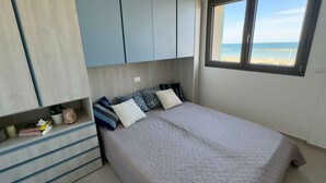 Un dormitorio con cama, ventana con vistas al mar y armario empotrado.