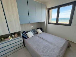 Ein Schlafzimmer mit Bett, einem Fenster mit Meerblick und einem Einbauschrank.
