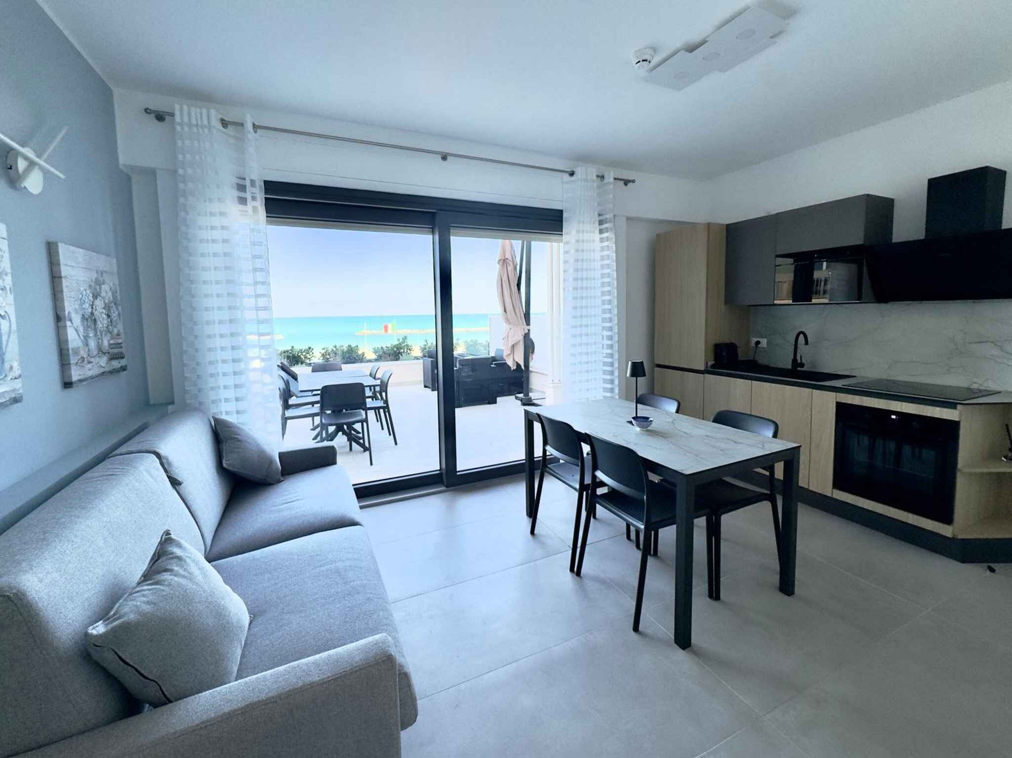 Um apartamento moderno com varanda, área de jantar e cozinha.