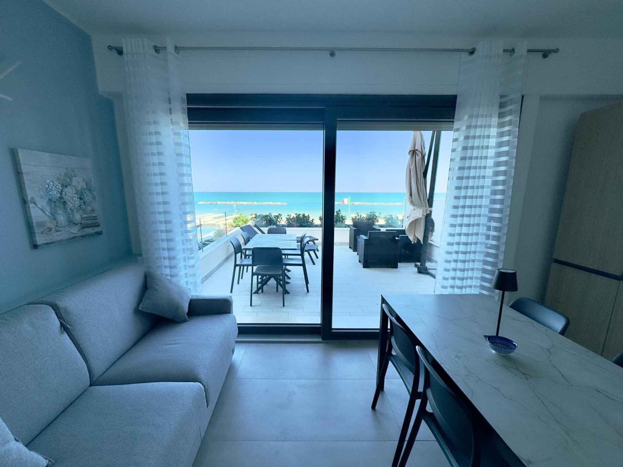 Una stanza con un divano, un tavolo da pranzo e vista sulla spiaggia.