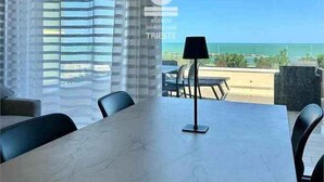Una habitación con una mesa, sillas, una lámpara y vistas al océano.