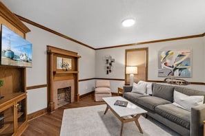Ein Wohnzimmer mit Kamin, einer Couch, einem Couchtisch und einem Fernseher.