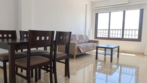 Un área de comedor con una mesa y sillas, un sofá, una mesita y un ventanal con vistas.