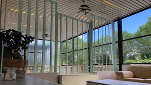Un intérieur moderne avec une table en bois, un canapé et une grande fenêtre donnant sur la forêt.