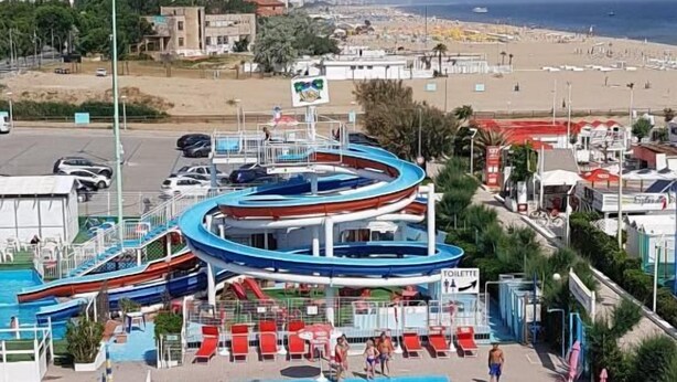 Un parc aquatique doté d’une grande piscine, de toboggans et de chaises longues.