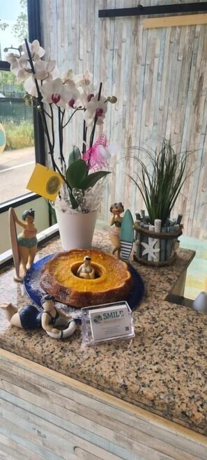 A kitchen counter with a cake, a small sign, and various decorative items. - Smile Beach Hotel (Riccione)