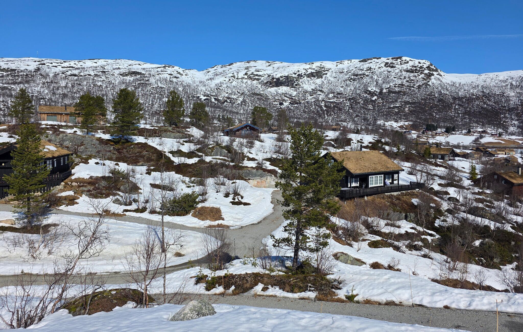 Une région montagneuse aux paysages enneigés, parsemée de plusieurs chalets en bois aux toits de chaume.