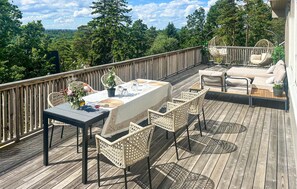 A wooden deck with a table and chairs, surrounded by a wooden railing, overlooking a forested area. - Nice home in Tjøme with WiFi (Tjøme)