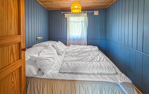 A room with a bed, wooden walls, a window with sheer curtains, and a hanging light fixture. - Nice home in Tjøme with WiFi (Tjøme)