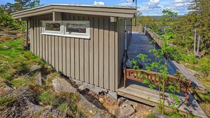 Eine kleine Hütte mit Fenster, einer Terrasse und einer Satellitenschüssel.