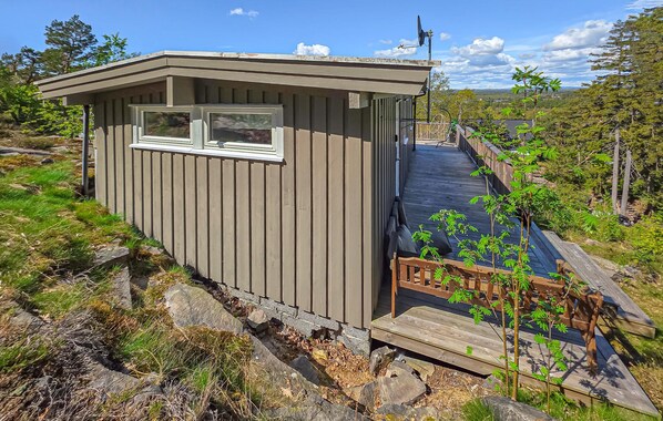 A small cabin with a window, a deck, and a satellite dish.