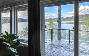 Une pièce dotée de grandes fenêtres donnant sur un lac et des montagnes.