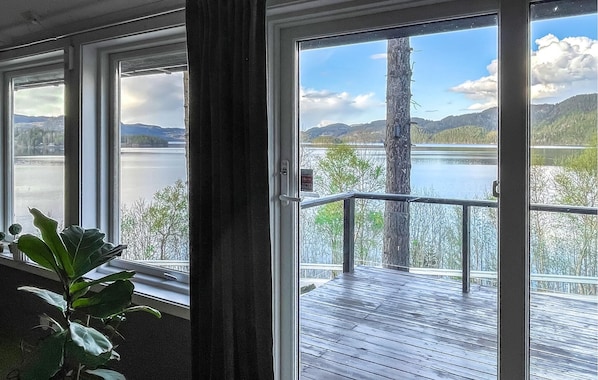 A room with large windows overlooking a lake and mountains.