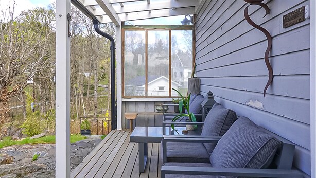 Un porche cubierto con una mesa y sillas, vista de una casa y una terraza de madera.