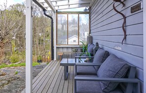 Eine überdachte Veranda mit Tisch und Stühlen, Blick auf ein Haus und eine Holzterrasse.