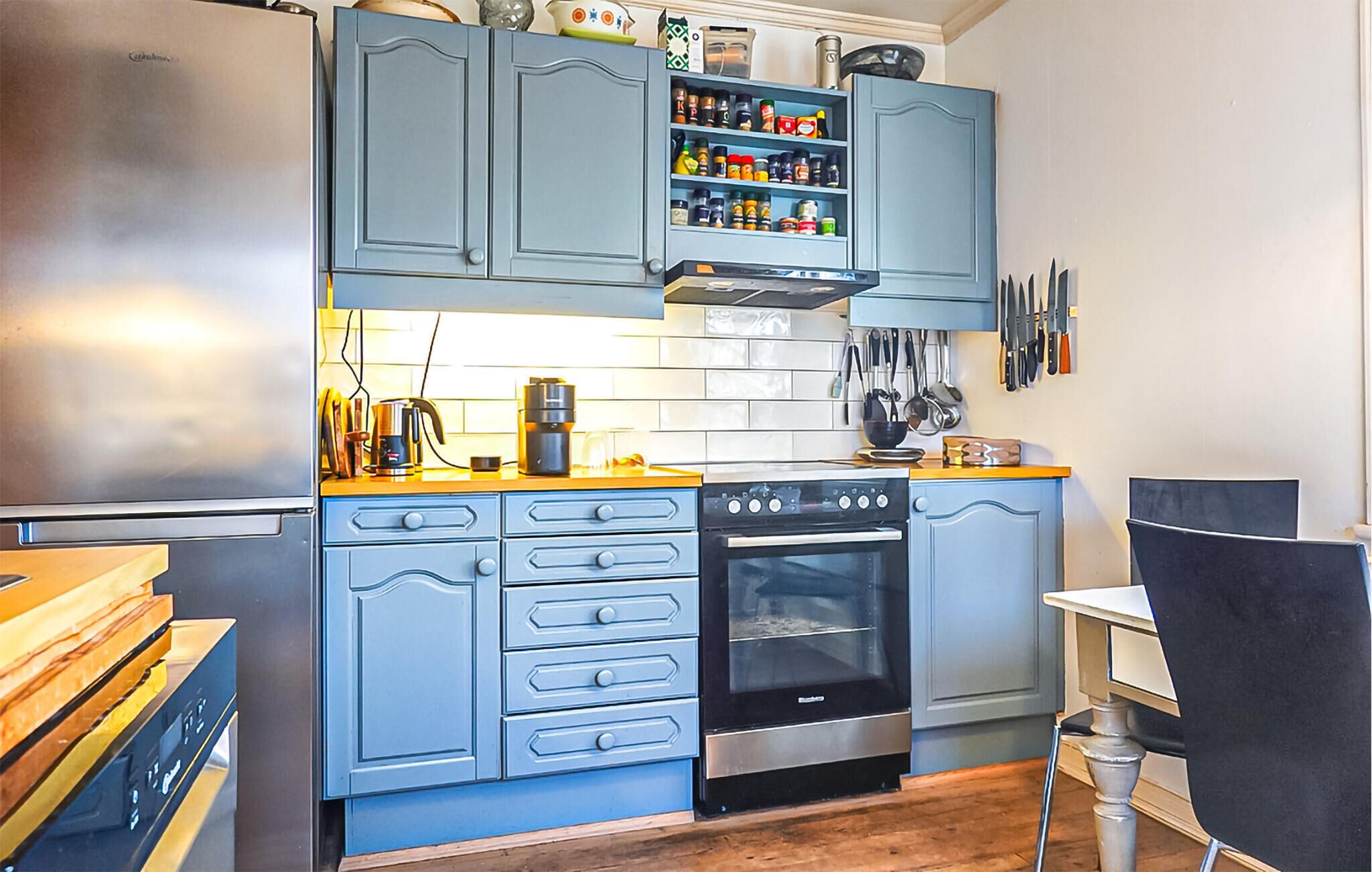 A kitchen with blue cabinets, a stove, oven, and a coffee maker.