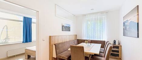 Et spiseområde med bord, stole, bænk og udsigt til det fri.