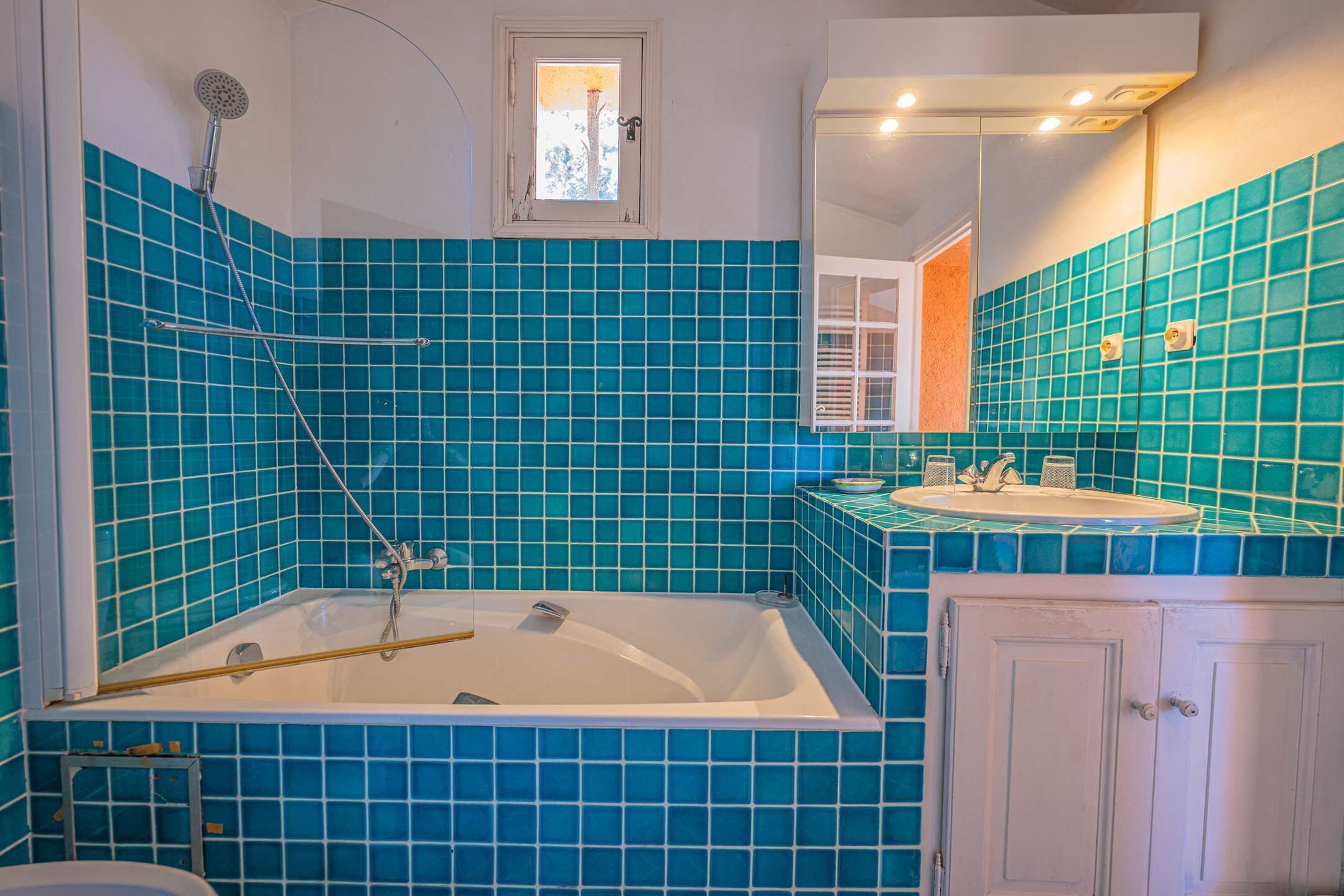 A bathroom with a bathtub, a shower, a sink, and a cabinet.