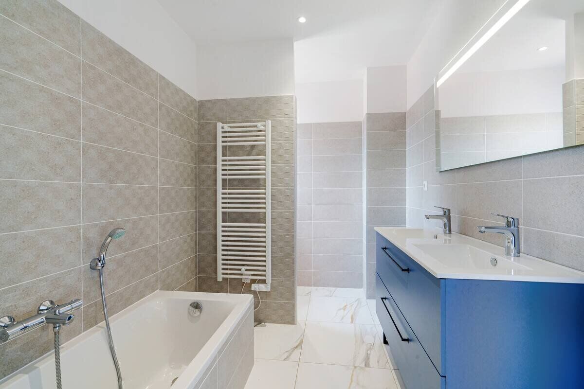 Un baño moderno con bañera, ducha, toallero y tocador con espejo.