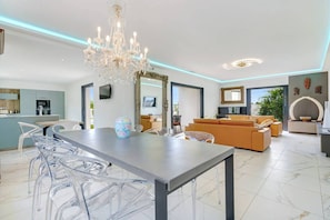 Ein modernes Wohnzimmer mit Essbereich, einer Chandelüster und einem großen Spiegel.