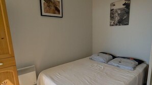 Ein Schlafzimmer mit einem Bett, einem Holzschrank, einem Heizkörper und zwei Bildern an der Wand.
