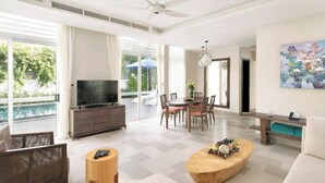 Amplia sala de estar con televisión, comedor y balcón con vista a la piscina.