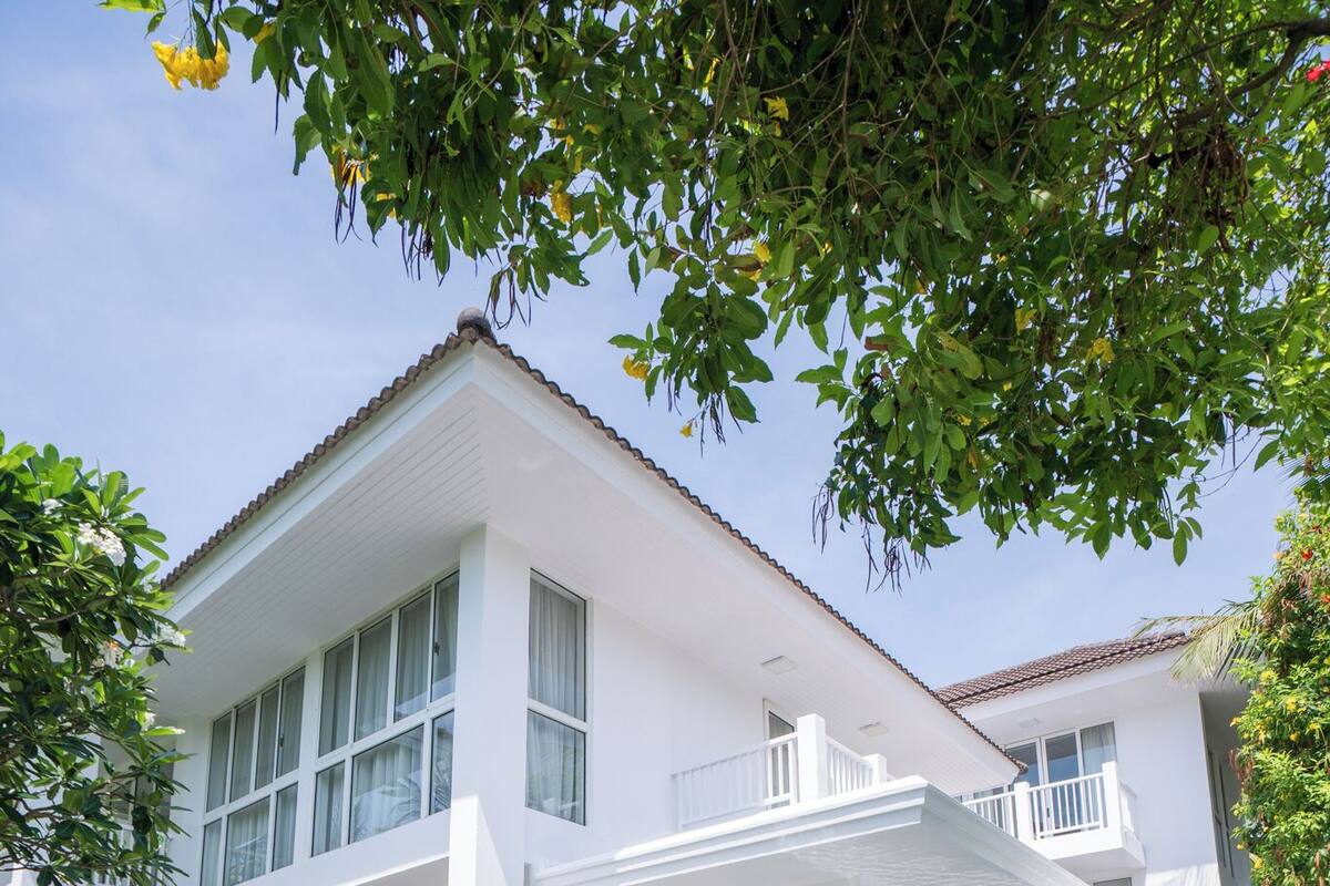 A two-story building with a swimming pool, large windows, and a balcony.