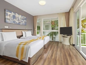 Une chambre d’hôtel avec deux lits, une télévision et un balcon donnant sur un espace verdoyant.