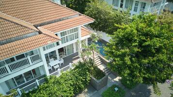 A multi-story building with a tiled roof, balconies, and a swimming pool.